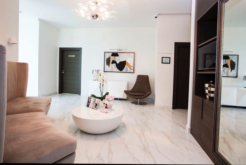 A modern and comfortable waiting room in a plastic surgery clinic, designed to provide a relaxing atmosphere for patients before their consultations and procedures. The space features stylish furnishings, soft lighting, and a calm ambiance to ensure a stress-free experience.